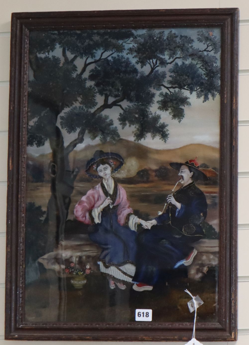 A 19th century Chinese reverse painting on glass of a lady and gentleman seated in a landscape, 56.5 x 38cm